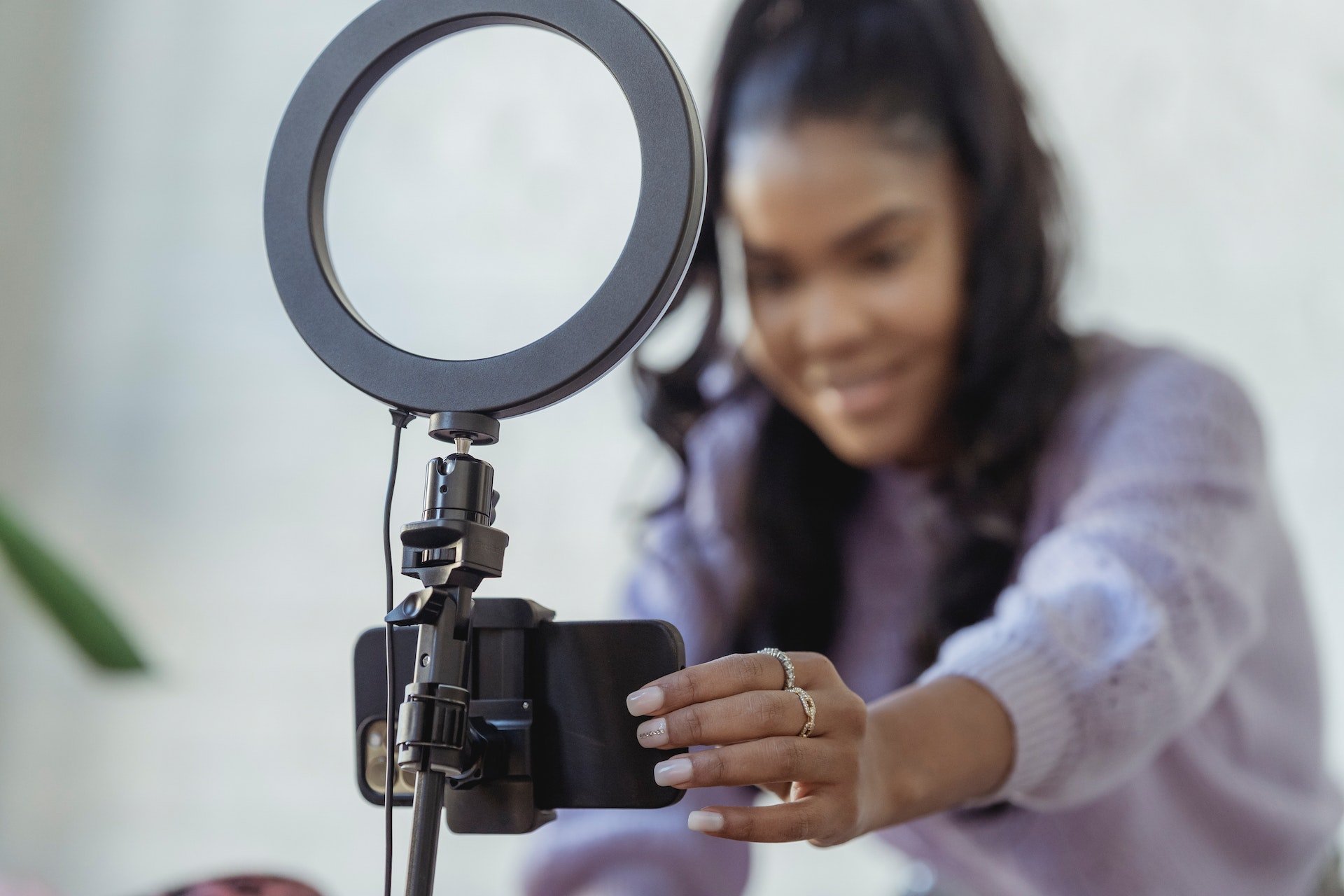 Woman setting up a phone to a ring light holder to capture good lighting