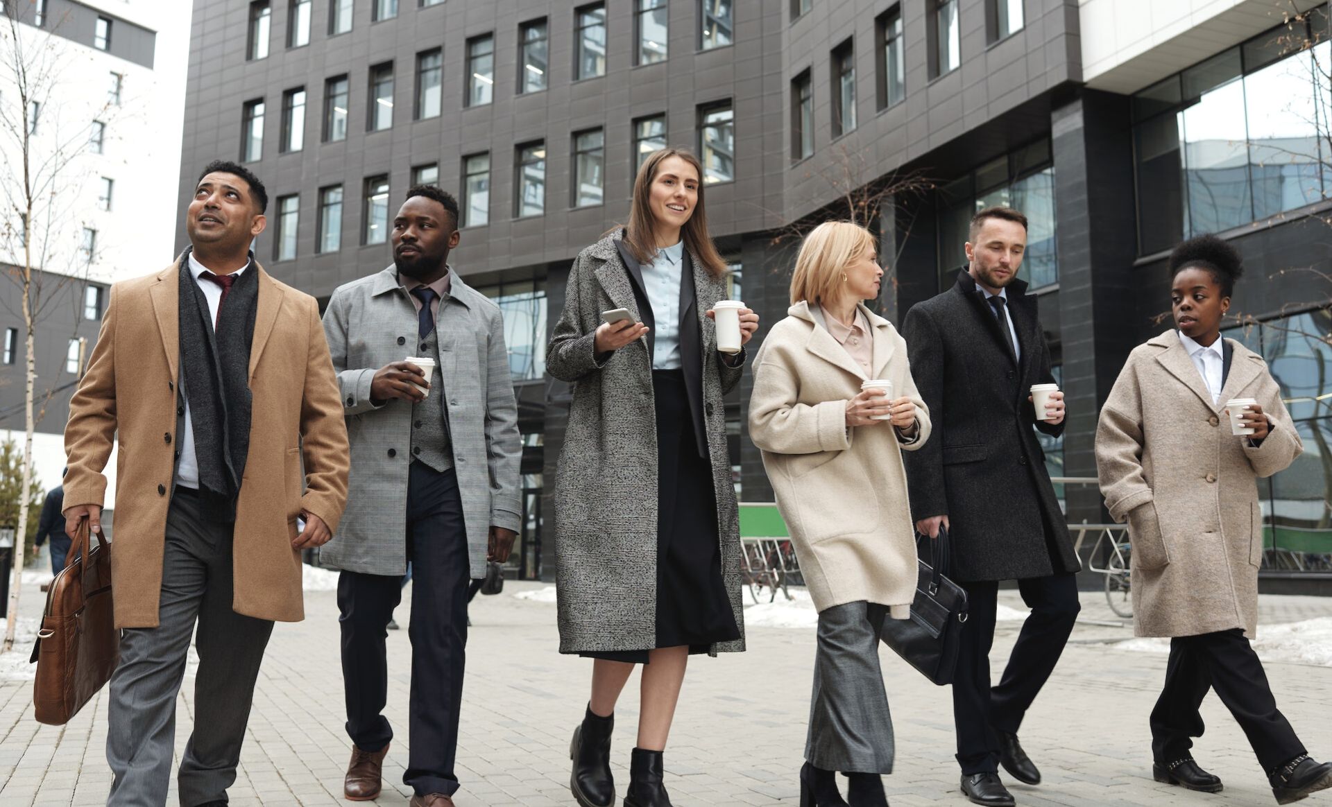 Group of interior design industry professionals walking along the street enjoying coffee. 