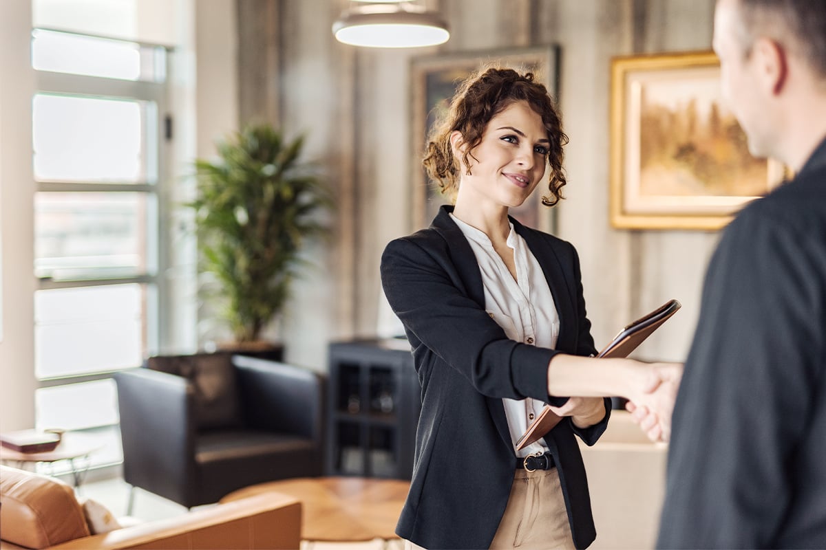 Women shaking hands with a man in a suit. 