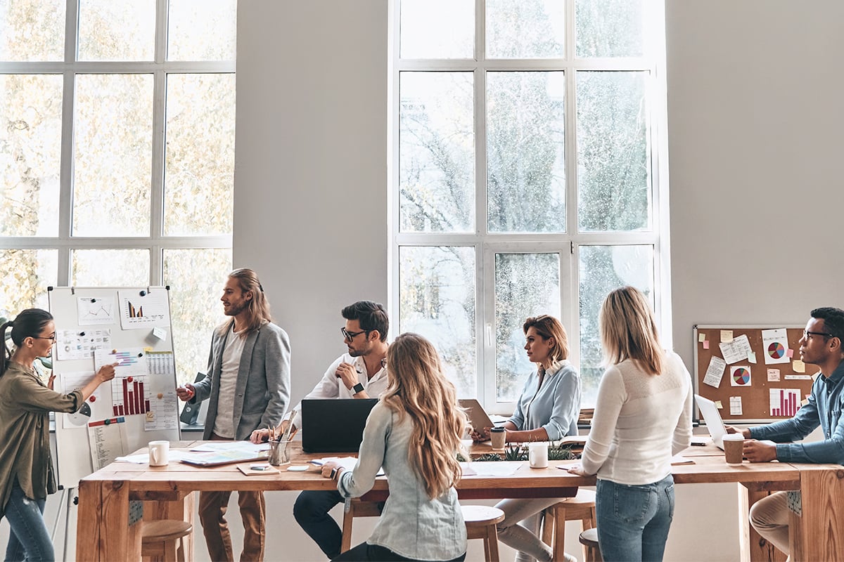 People sitting in room looking at white board presentation